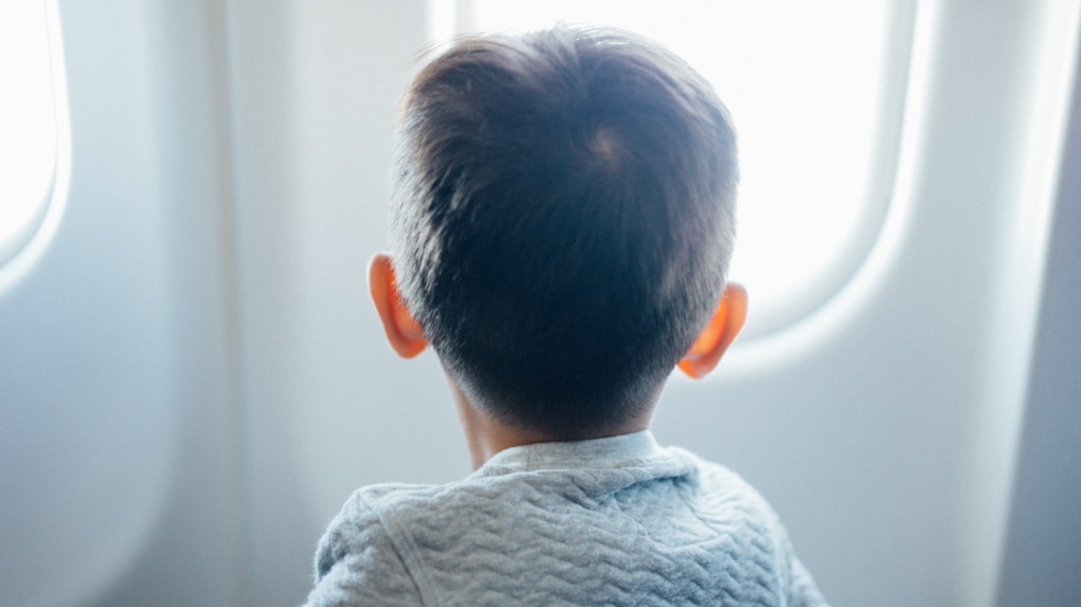 Young boy looks outside an airplane window